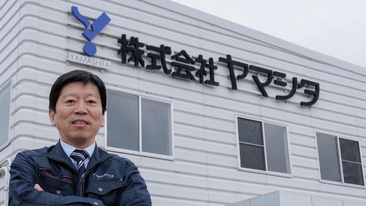 株式会社ヤマシタの外観の前に立つ代表取締役の福山氏の写真